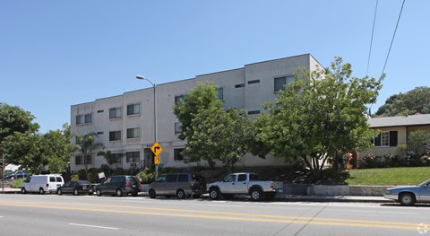 A street view of a building with cars parked in front.