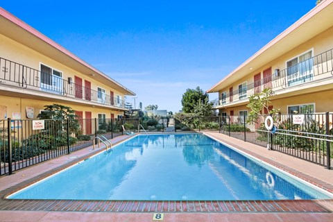 A swimming pool in front of a building with a red and white striped awning.
