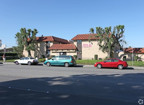 A red car is parked in front of a building with a sign that reads "Parking.".