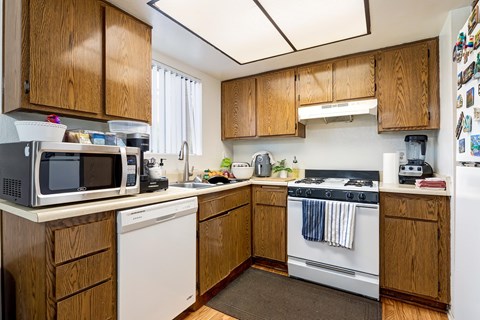 A kitchen with wooden cabinets and a white dishwasher.