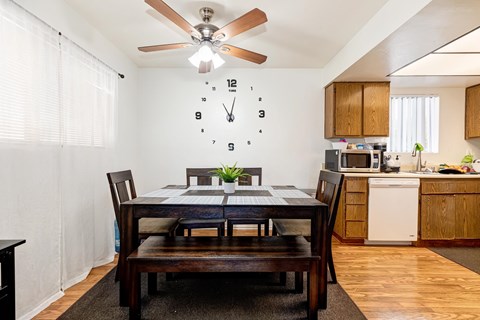 A dining room with a table set for two and a clock on the wall.