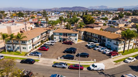 A parking lot with several cars and a building in the background.