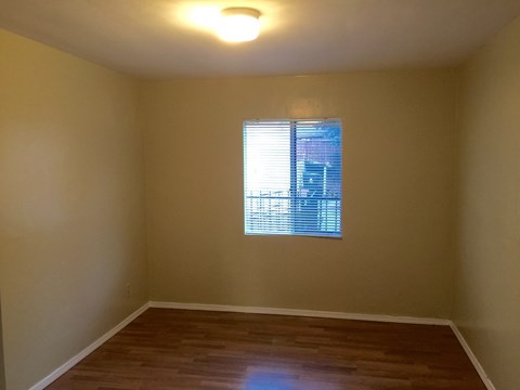 A room with a window and wooden flooring.