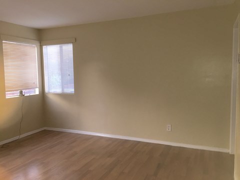 A room with wooden floors and a window with blinds.