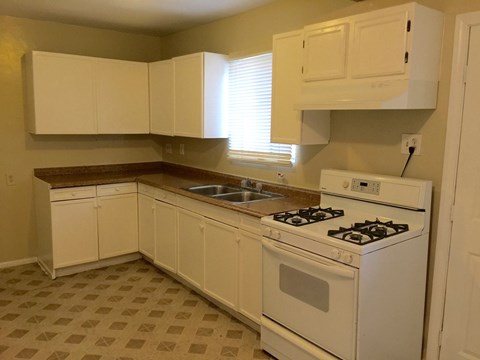 A kitchen with white cabinets and a white stove top oven.