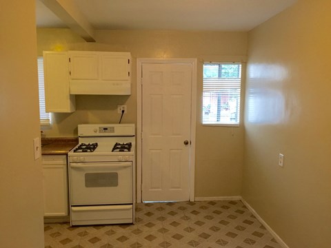 A kitchen with a white stove and a white door.