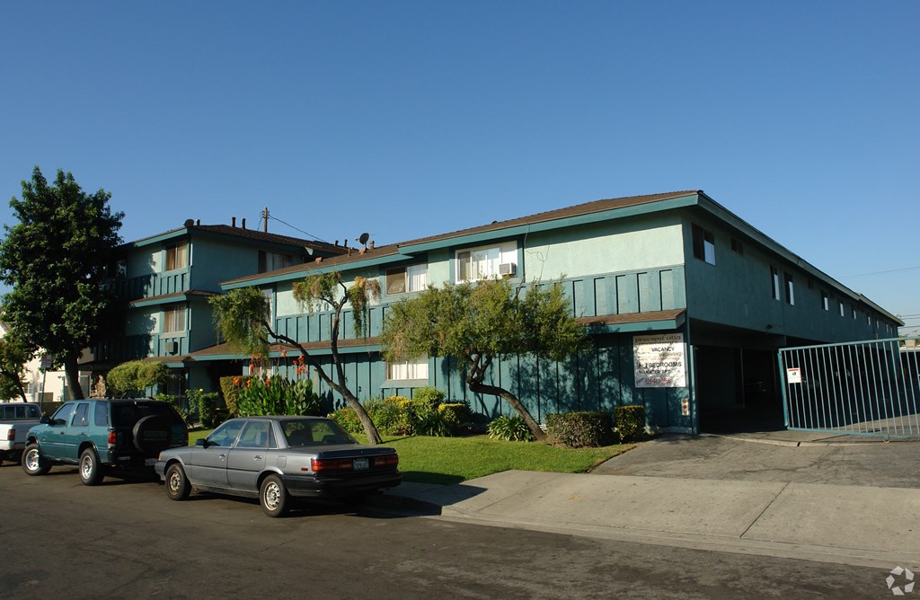 A blue building with a gate in front and cars parked in front.