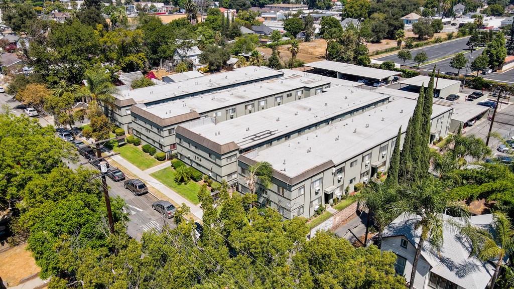 A large grey building surrounded by trees and a parking lot.