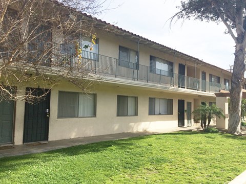 A building with a balcony and a tree in front of it.