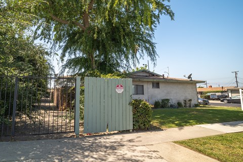 A white house with a red and white sign on a gate.