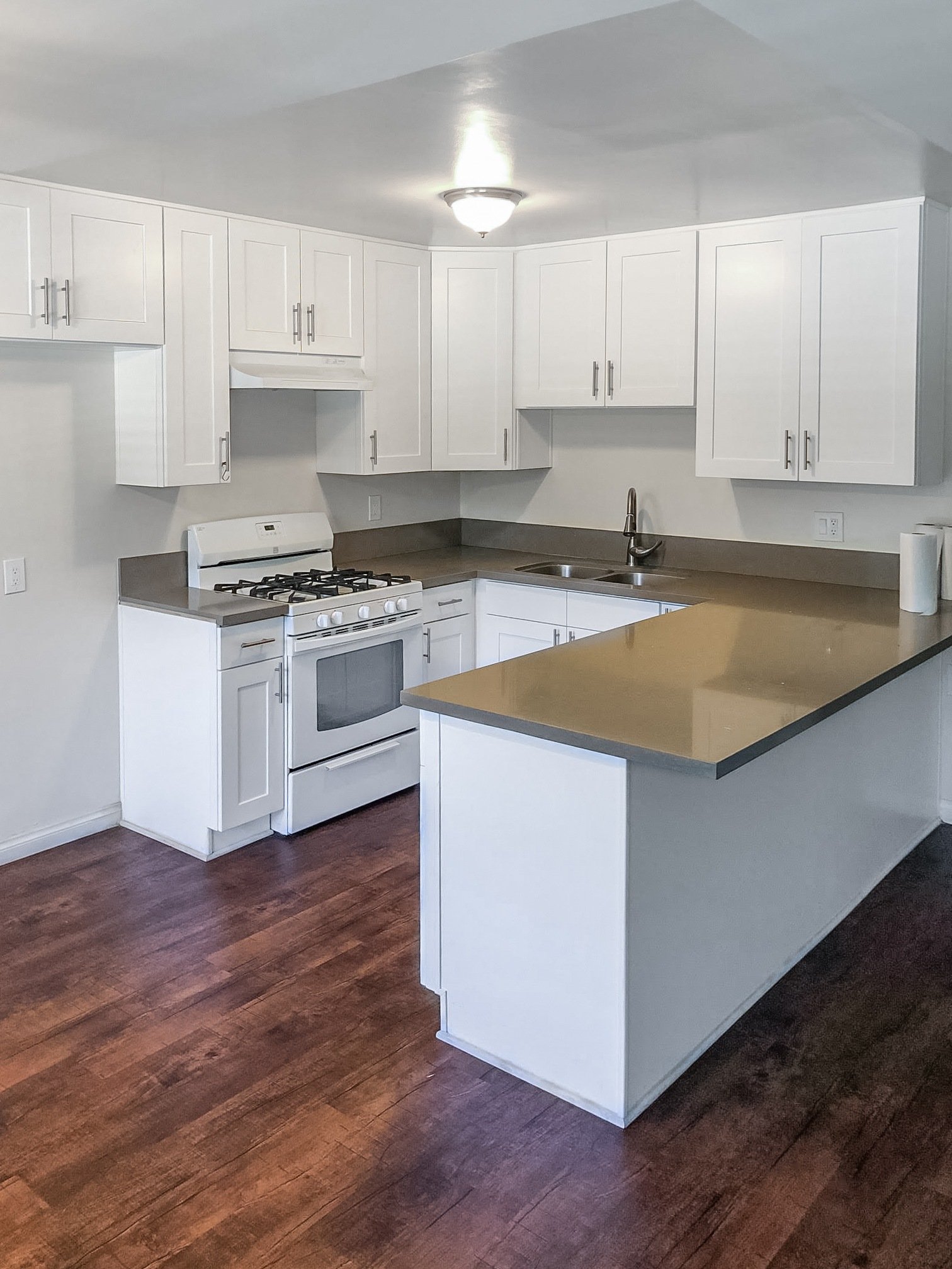 A kitchen with white cabinets and a wooden floor.