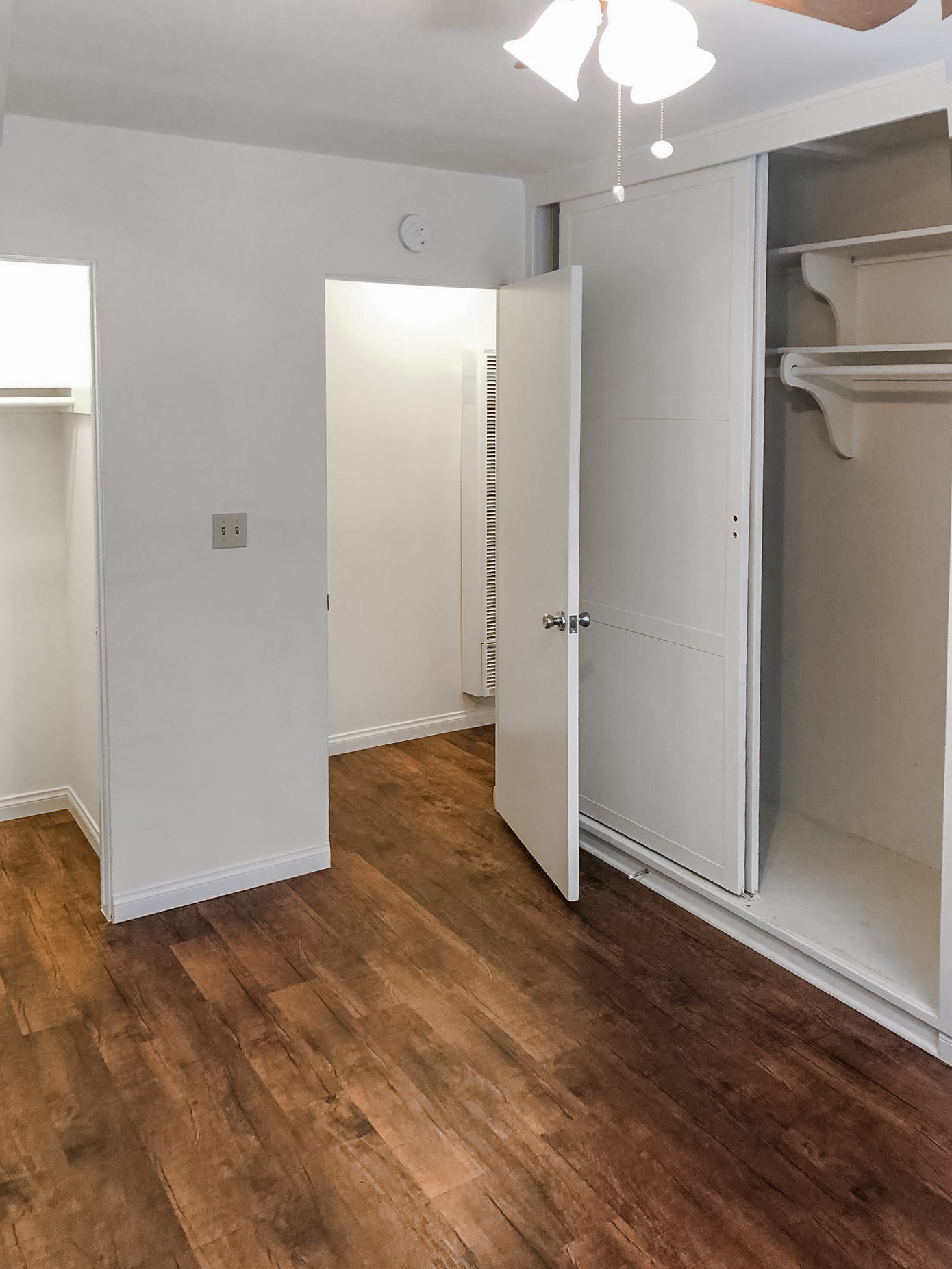 A white door is open to a room with wood flooring.
