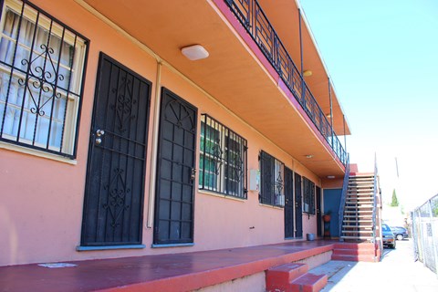 A building with a red staircase leading to a blue door.