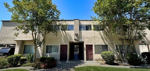 A building with a red door and a tree in front.
