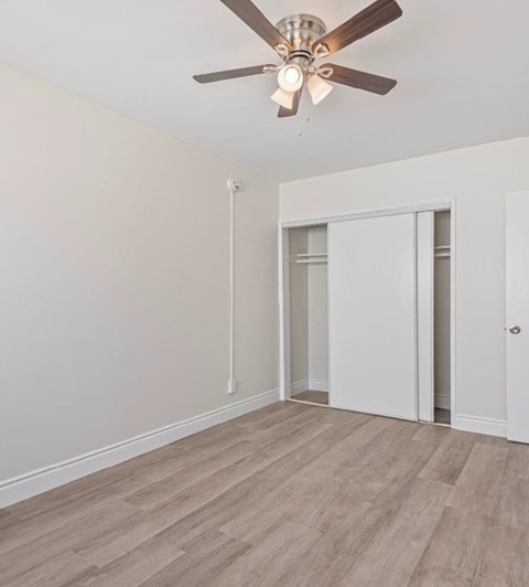 A room with a ceiling fan and light fixture, a door, and a window.