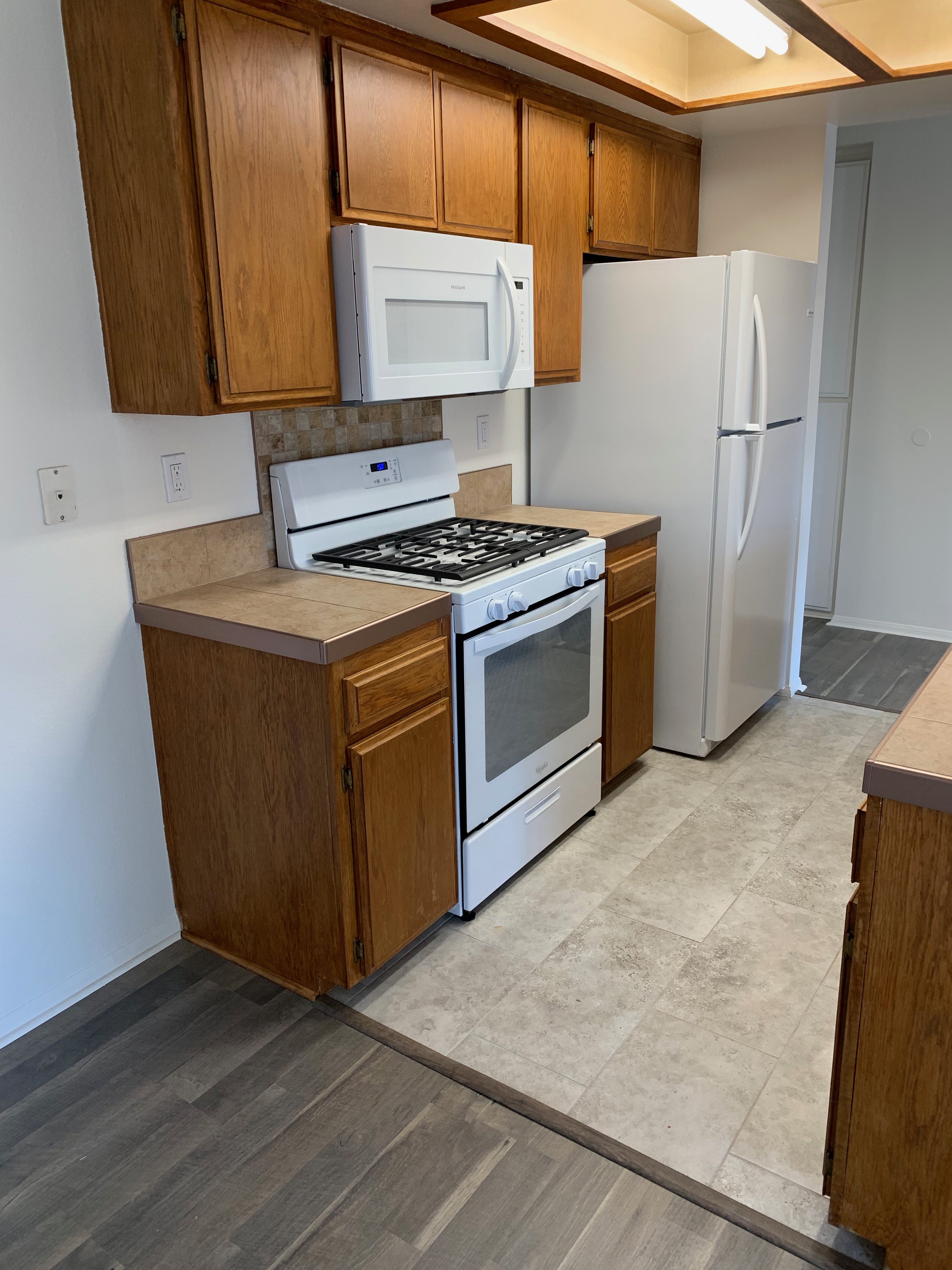 A kitchen with a stove, microwave, and refrigerator.