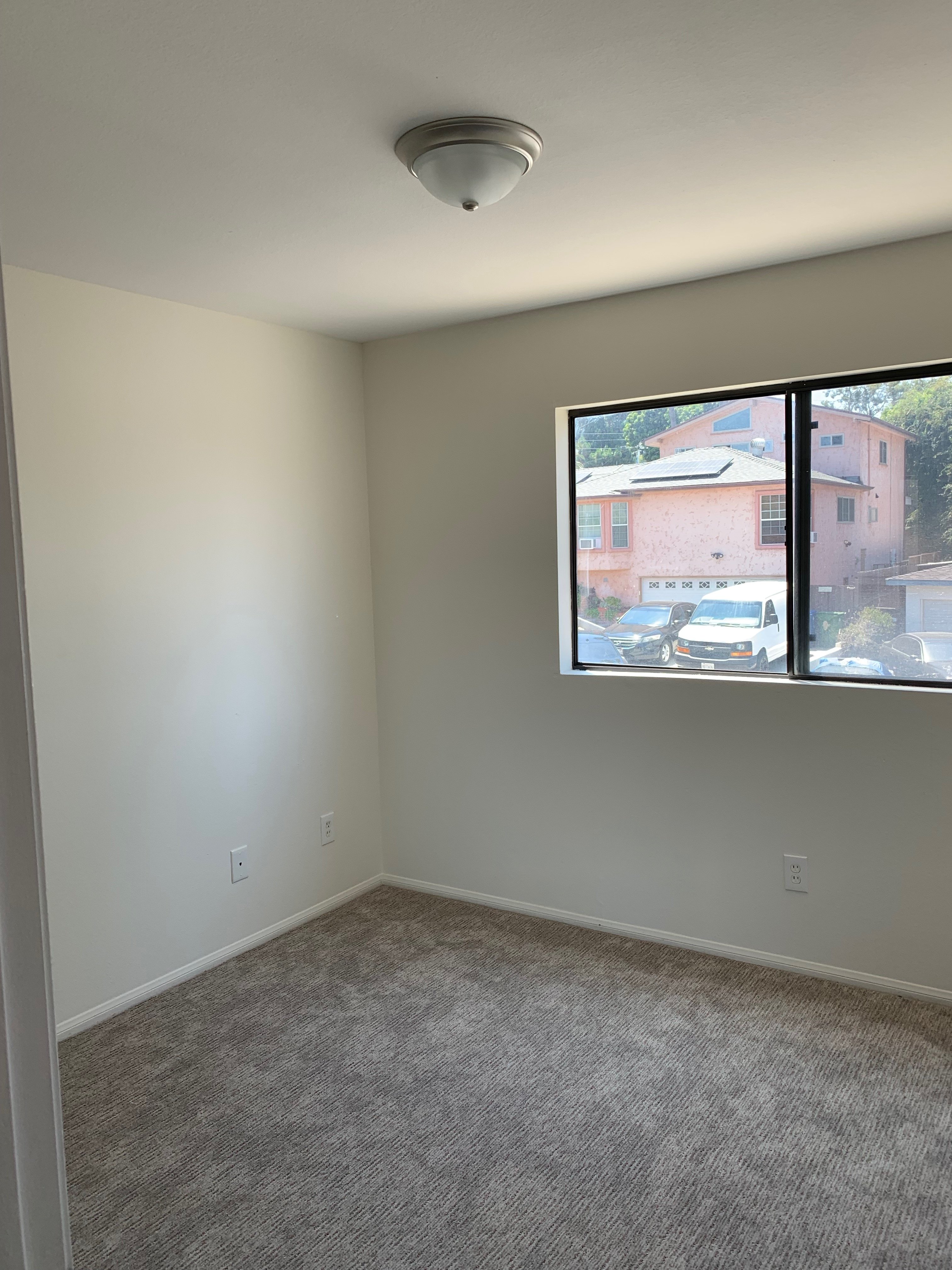 A room with a window showing a view of houses outside.