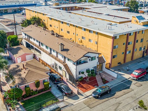 A yellow apartment building with a red car parked in front.