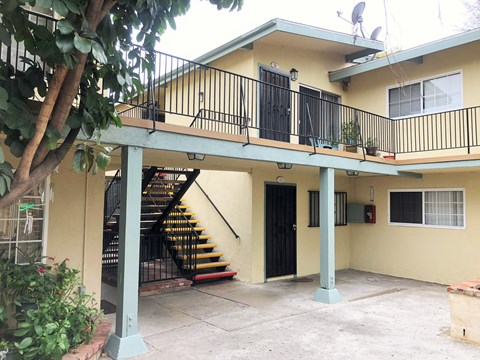 A yellow house with a black door and a staircase.