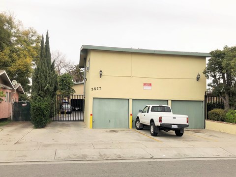 A white pickup truck is parked in front of a yellow garage.