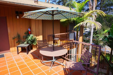 A patio with a table and chairs under an umbrella.