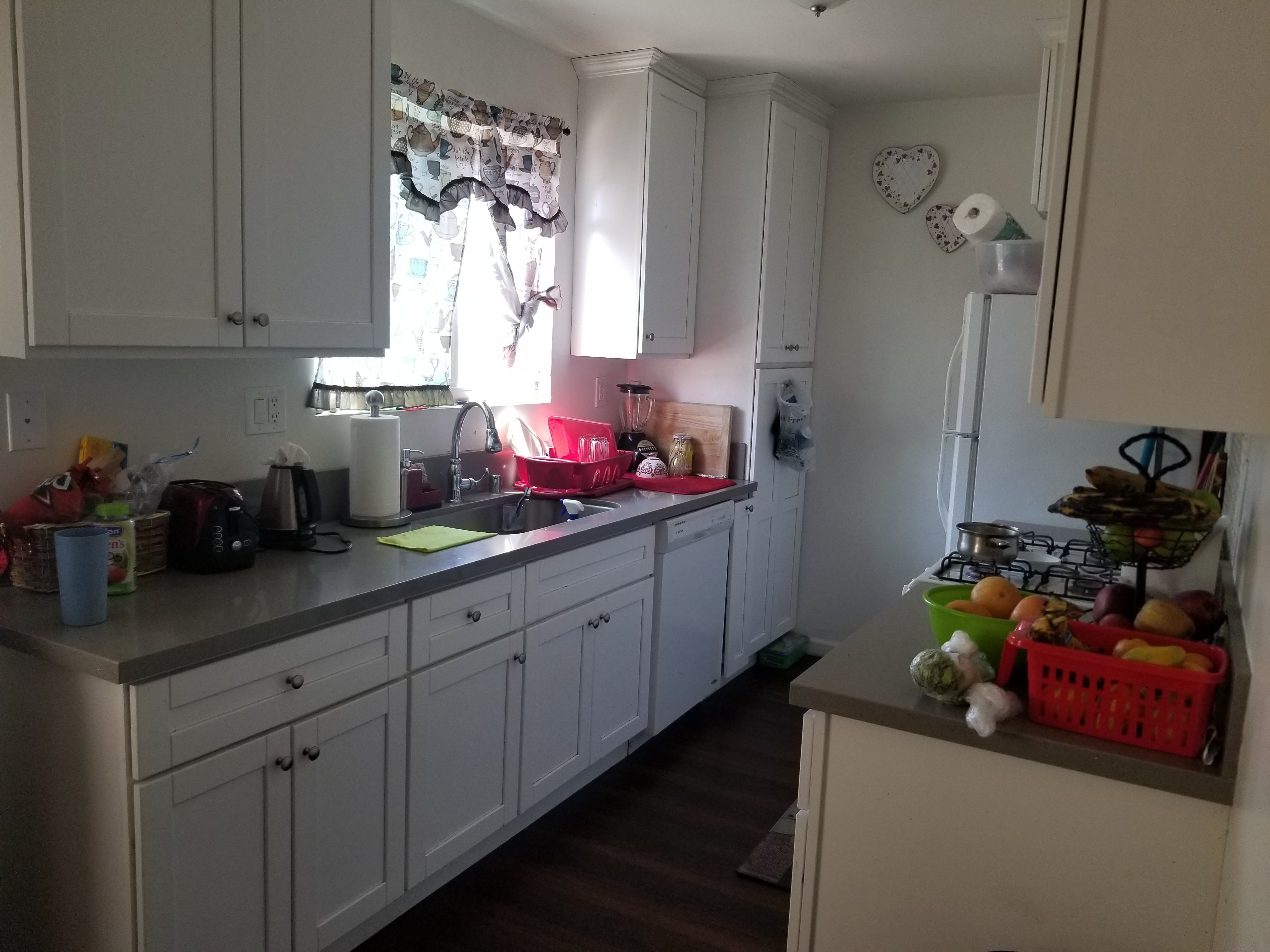 A kitchen with white cabinets and a counter with a basket of fruit on it.