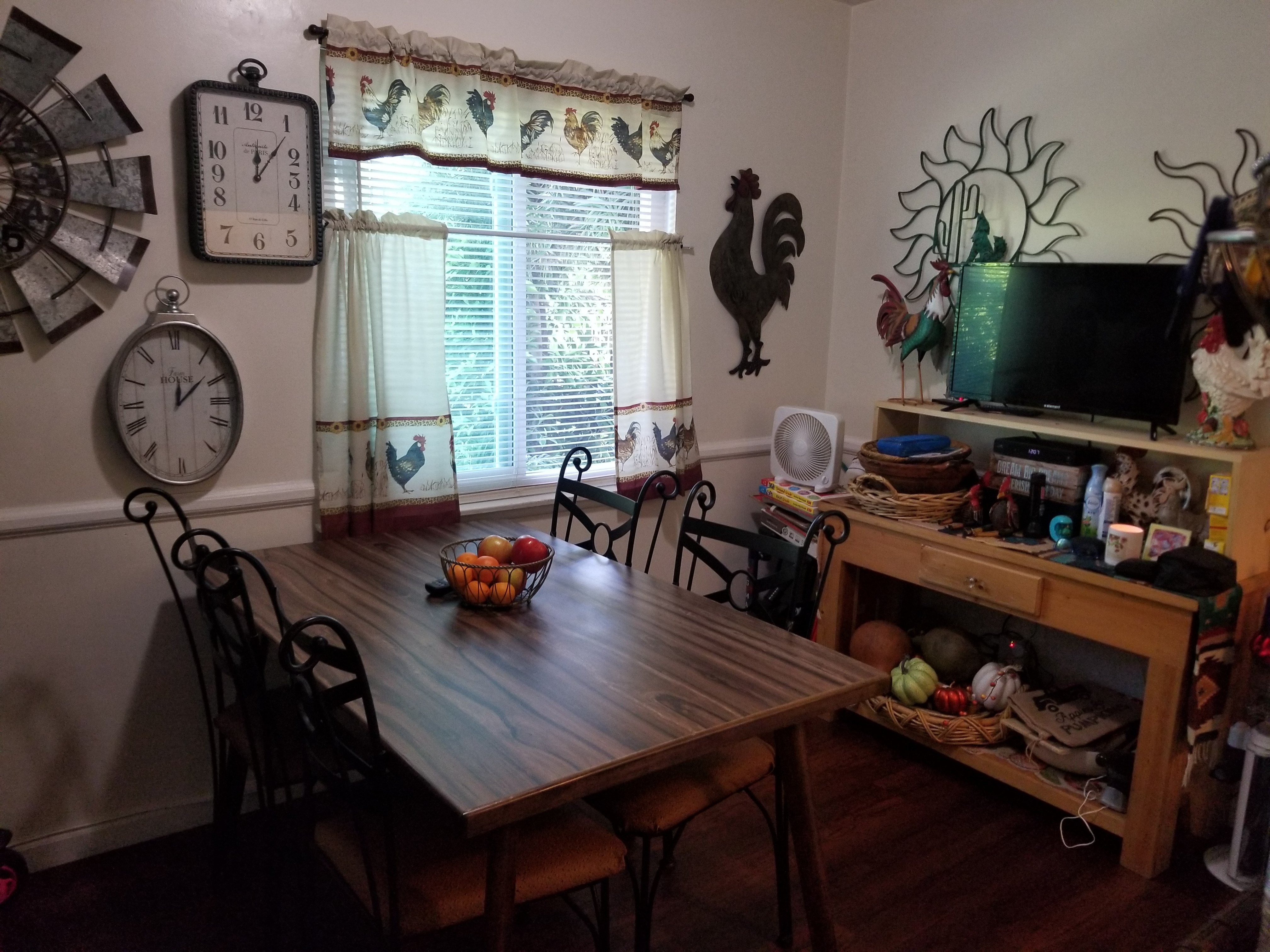 A wooden dining table with chairs and a bowl of fruit on it.