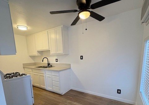 A kitchen with a fan on the ceiling and wooden flooring.