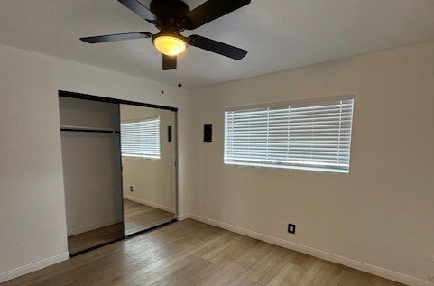 A room with a ceiling fan and wooden flooring.