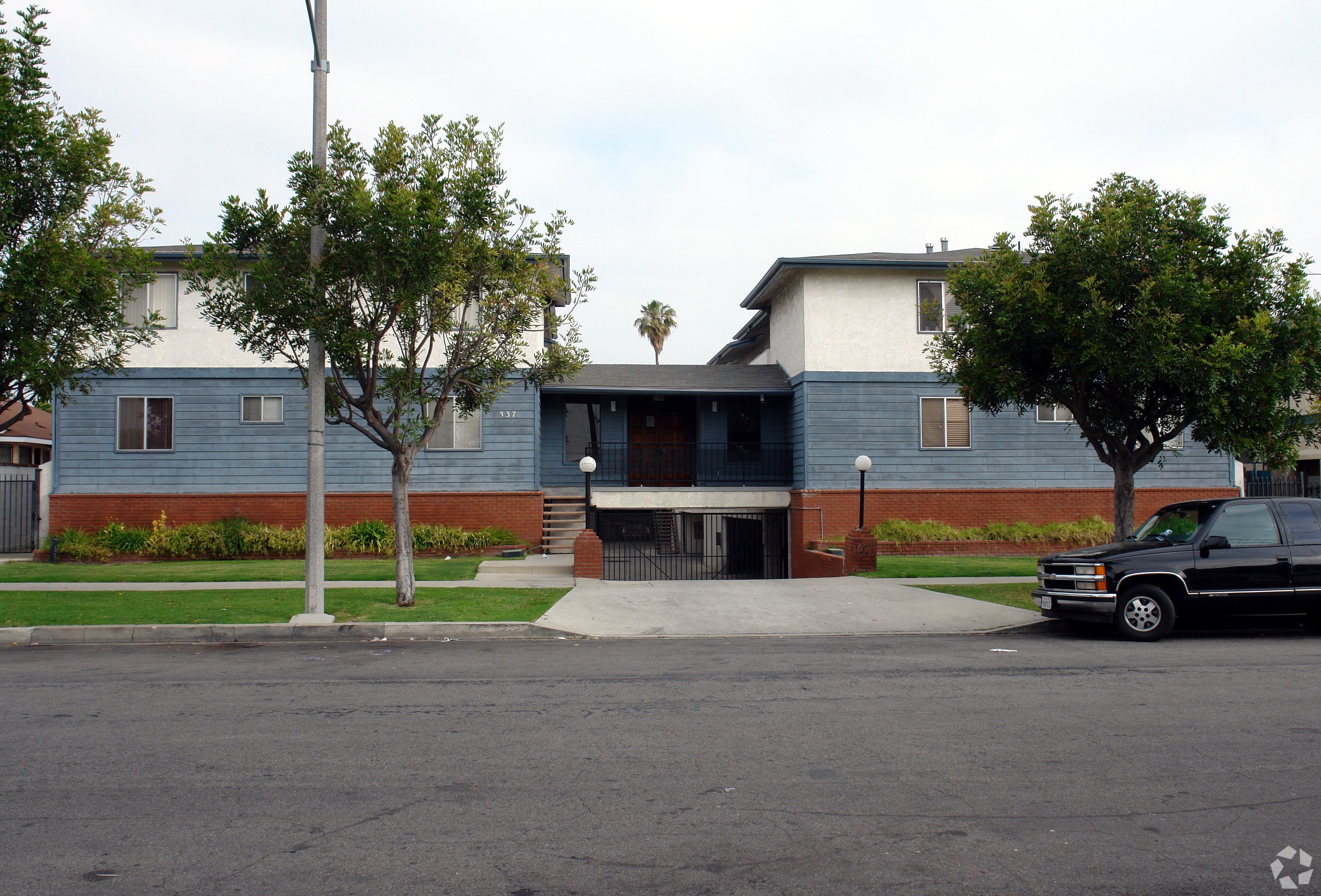 A black truck is parked on the street in front of a blue building.