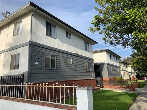 A grey house with a white fence in front.