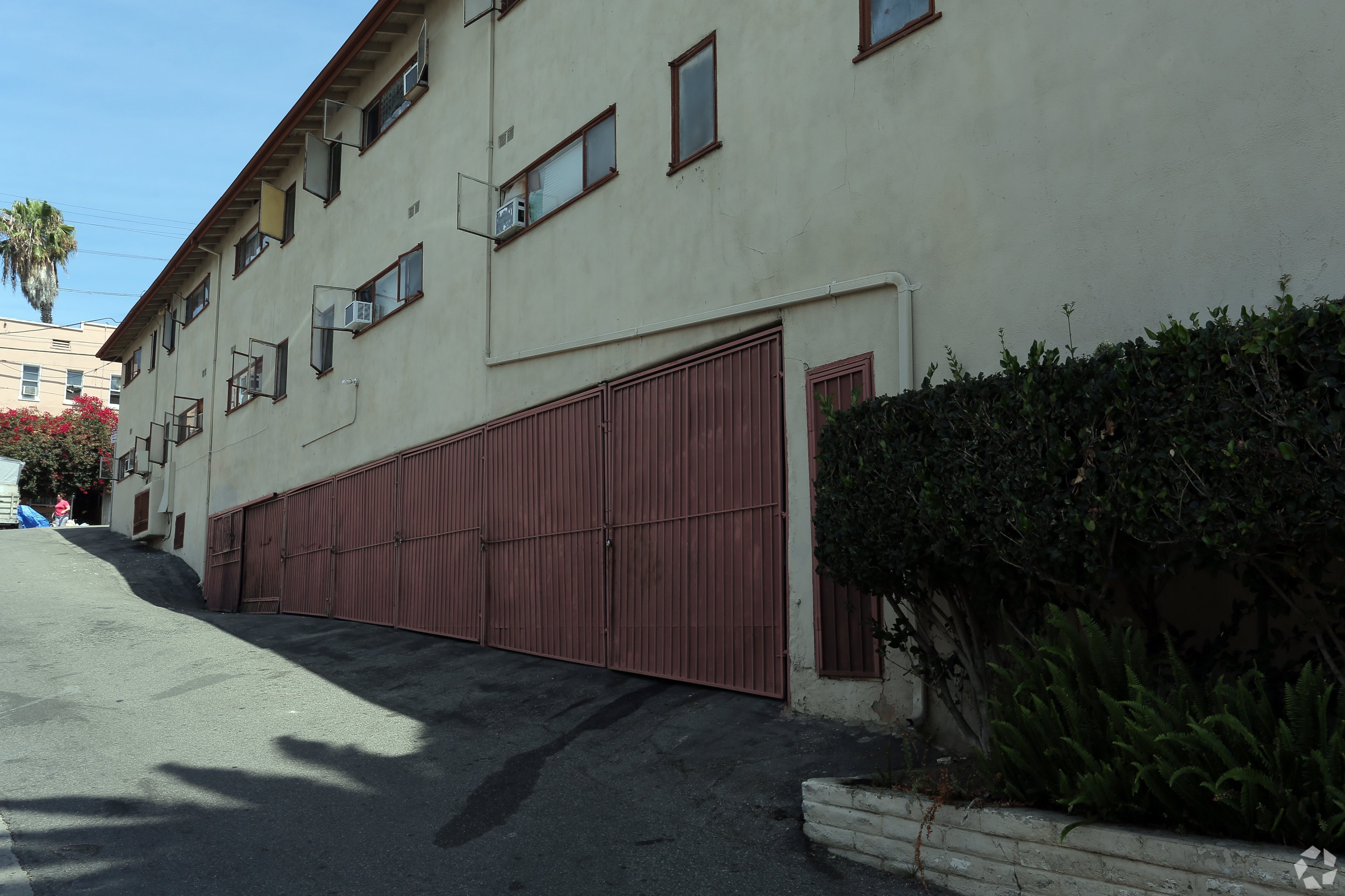 A building with a red garage door and a tree in front.