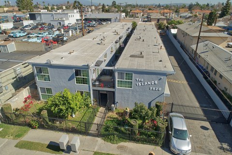 A parking lot with a white van parked in front of a building with a sign that says "The Island".