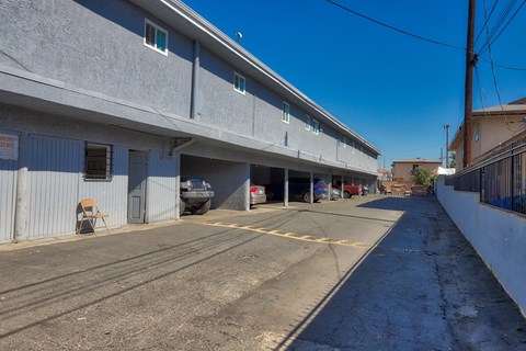 A parking lot with a building on the left and a car parked in the garage.