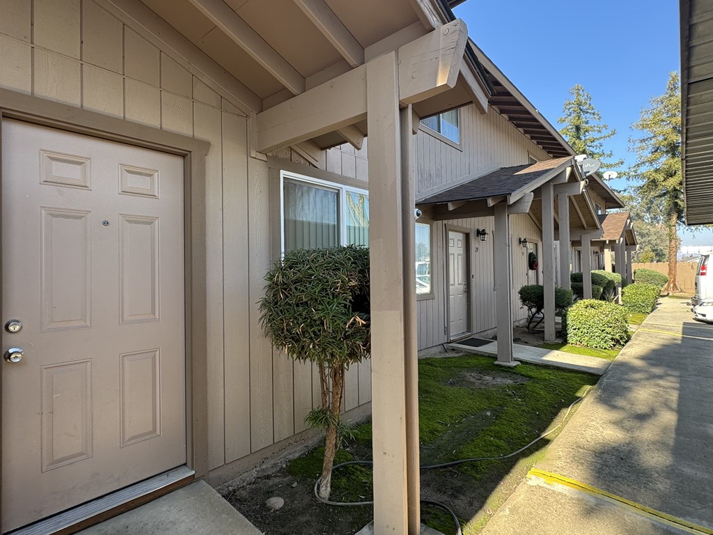 A house with a brown door and a small tree in front.
