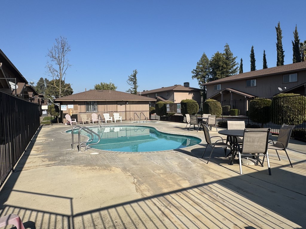 A pool surrounded by chairs and a fence.