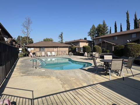 A pool surrounded by chairs and a fence.