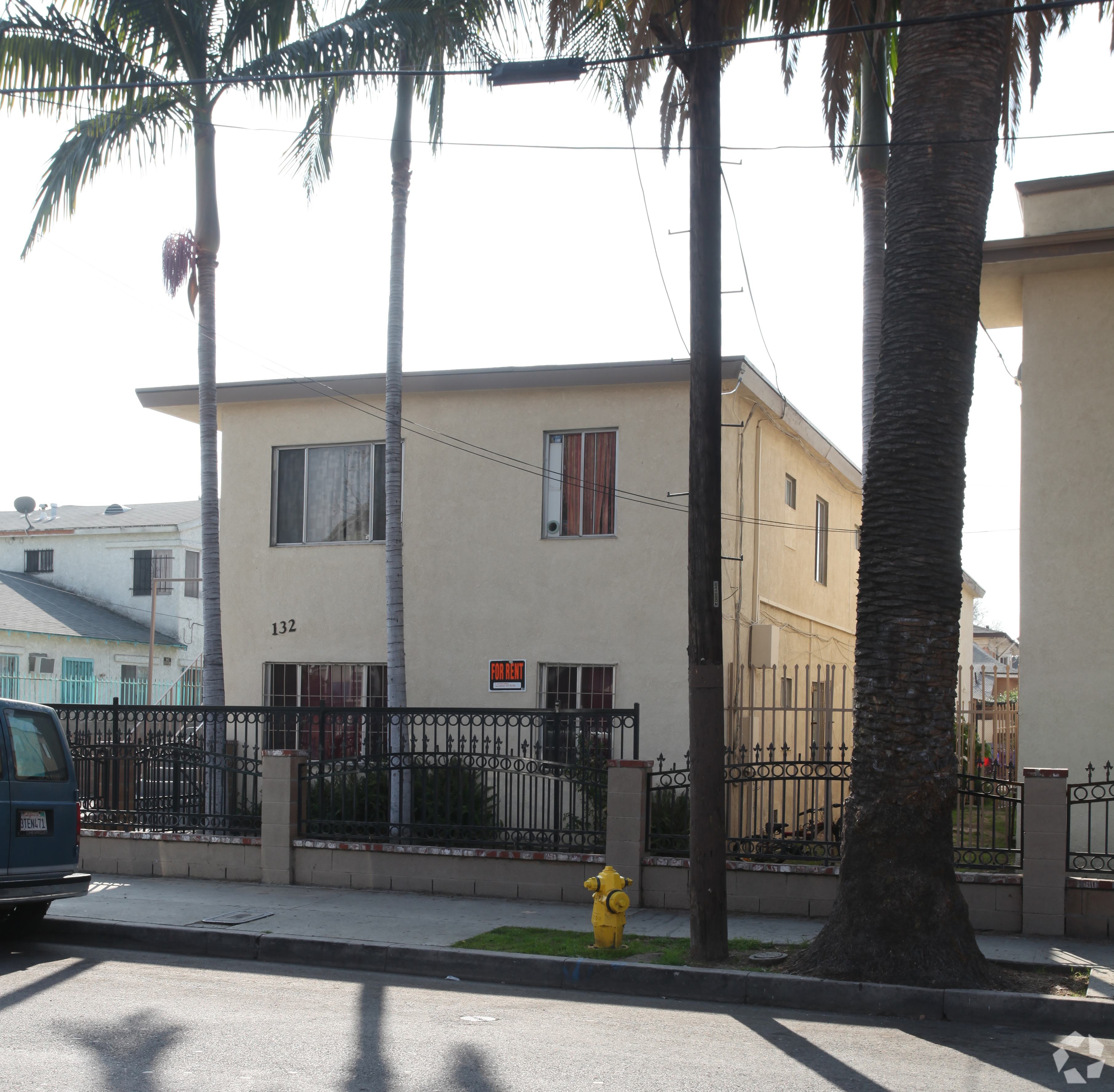 A house with a black fence and a yellow fire hydrant in front.