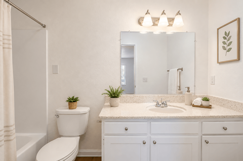 A white bathroom with a toilet, sink, and mirror.