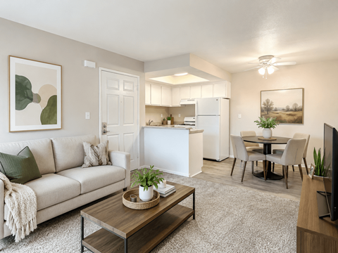 A living room with a couch, coffee table, and a dining area in the background.