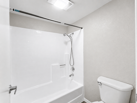 A white bathroom with a tub, toilet, and shower.