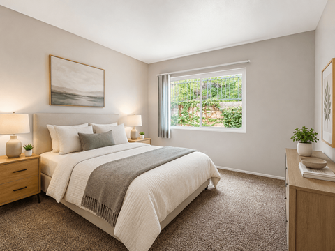 A bedroom with a large bed and a window overlooking a garden.