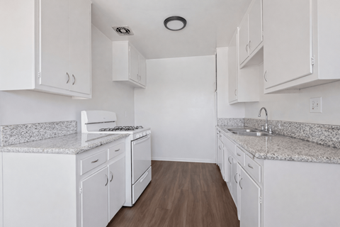 A kitchen with white cabinets and granite countertops.