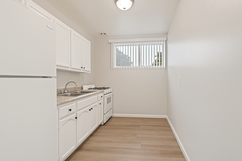 A kitchen with white cabinets and a window.
