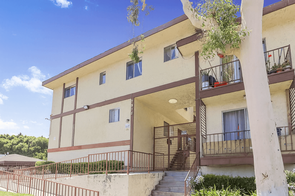 A building with a balcony and a tree in front of it.