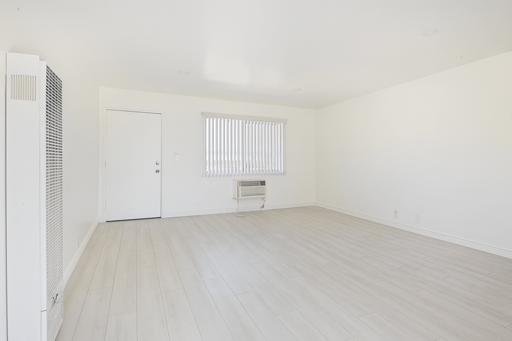 A room with a white door and a window with blinds.