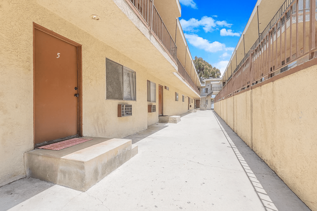 A narrow alley with a brown door on the left and a white door on the right.