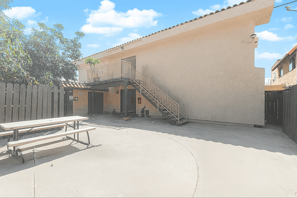 A patio with a bench and a building with a staircase.