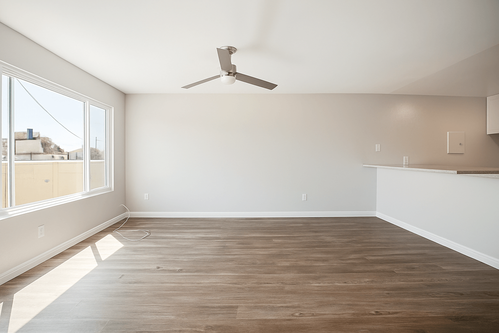 A room with a ceiling fan and wooden flooring.