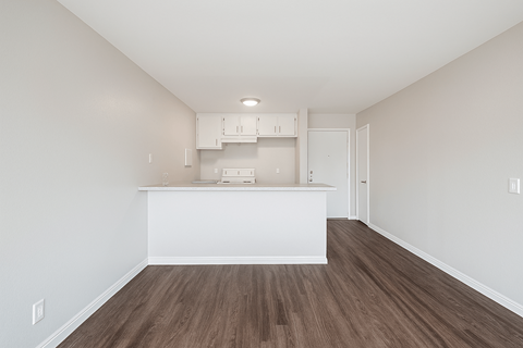 A kitchen with white cabinets and a wooden floor.